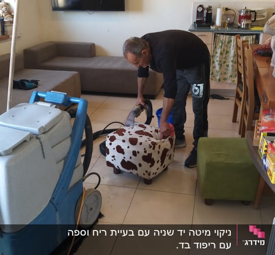 אדם מנקה כורסה עם מכונת ניקוי מקצועית